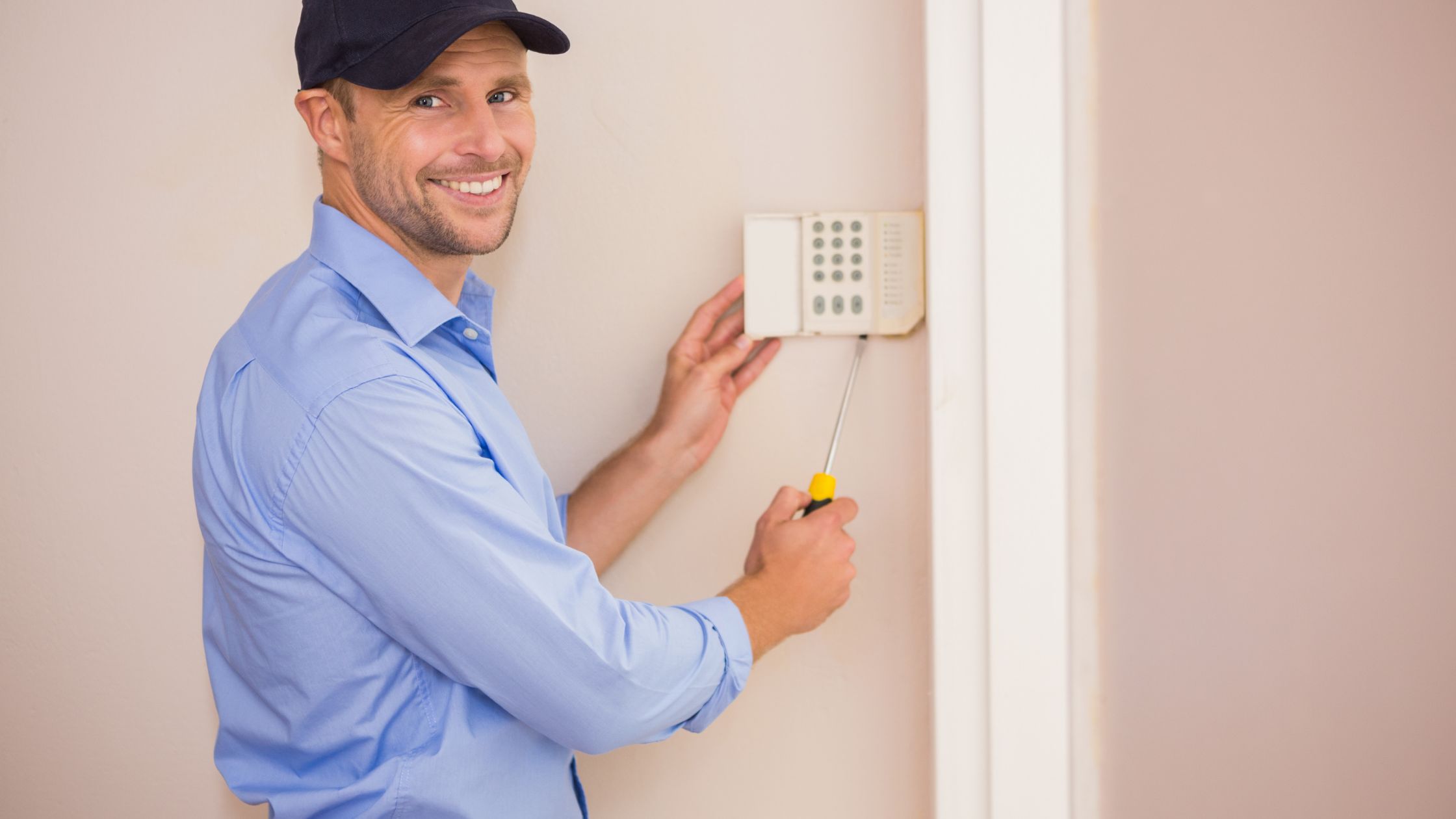 Smiling Handyman Fixing An House Alarm System
